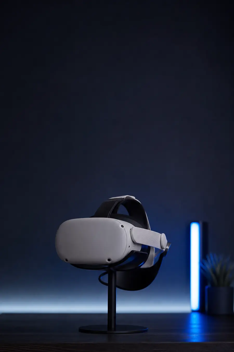 A VR headset resting on a stand on a dark desk.