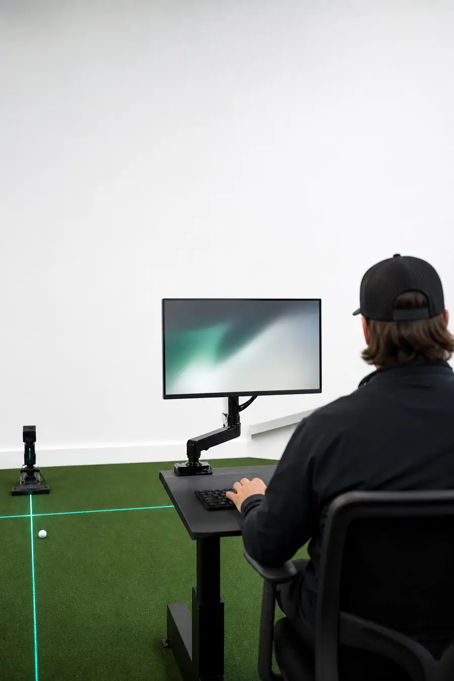 A gaming desk on a turf-green mat in a bright fitting studio.