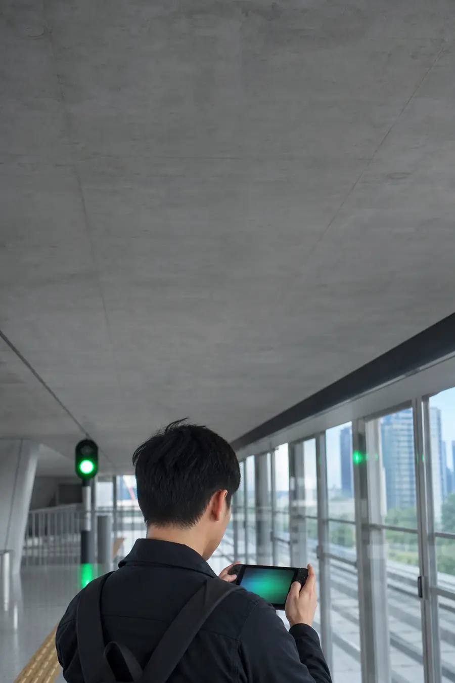 A commuter on a train platform playing a handheld gaming PC.