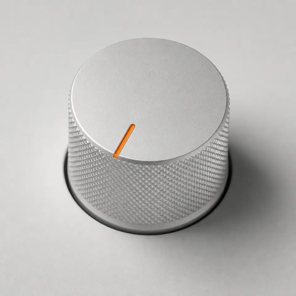 Close-up of an aluminium knob with an orange indicator line.